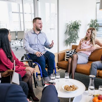 Man in a wheelchair addressing a meeting room filled with people