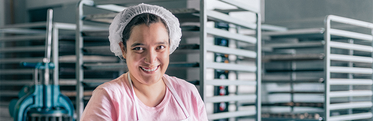 Woman in bakery with a tray of scones smiling happily