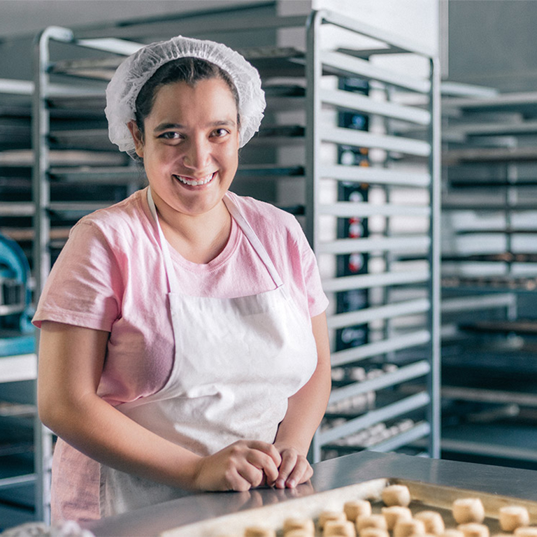 Woman in a bakery with a tray of biscuits smiling