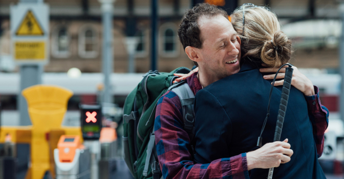Man embracing someone out the front of a train station.