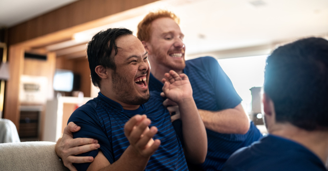 Young person with a disability laughing with a friend.