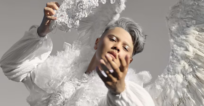 Sheldon Riley wearing white angle wings, holding a white mask in costume.