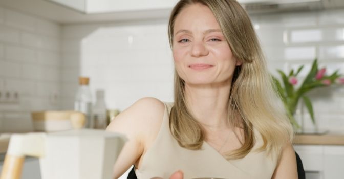 A woman in a wheelchair is sitting at her kitchen table and smiling.