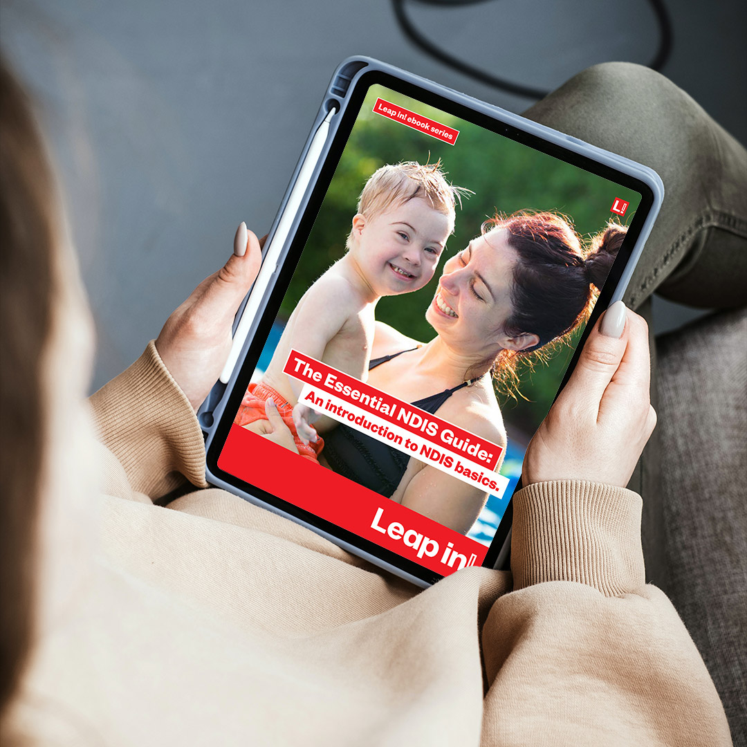 Overshoulder view of a woman holding an ipad pro with The Essential NDIS Guide showing on the screen