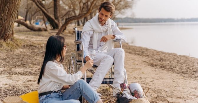 A man and a woman are having a picnic date on the beachfront.