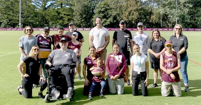 A group of participants and the organisers of Game Changer Program are in a football field standing as a group and smiling at the camera.