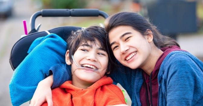 A brother and sister are hugging and smiling.