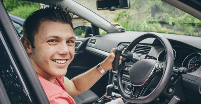 A man sits in a vehicle with a modified steering wheel.