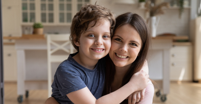 A young mother embracing preschool son, sitting on a couch at home