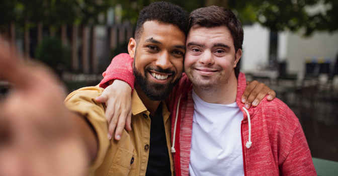 Young man with disability and his support worker taking a selfie.