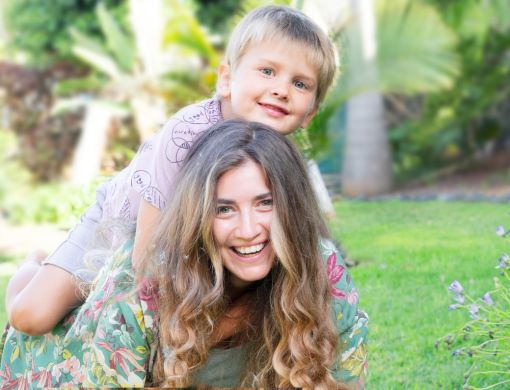 Woman lying on the grass with a young boy on her back