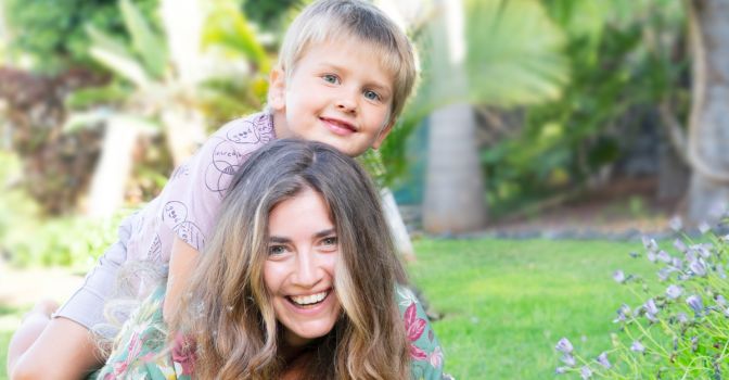 Woman lying on the grass with a young boy on her back