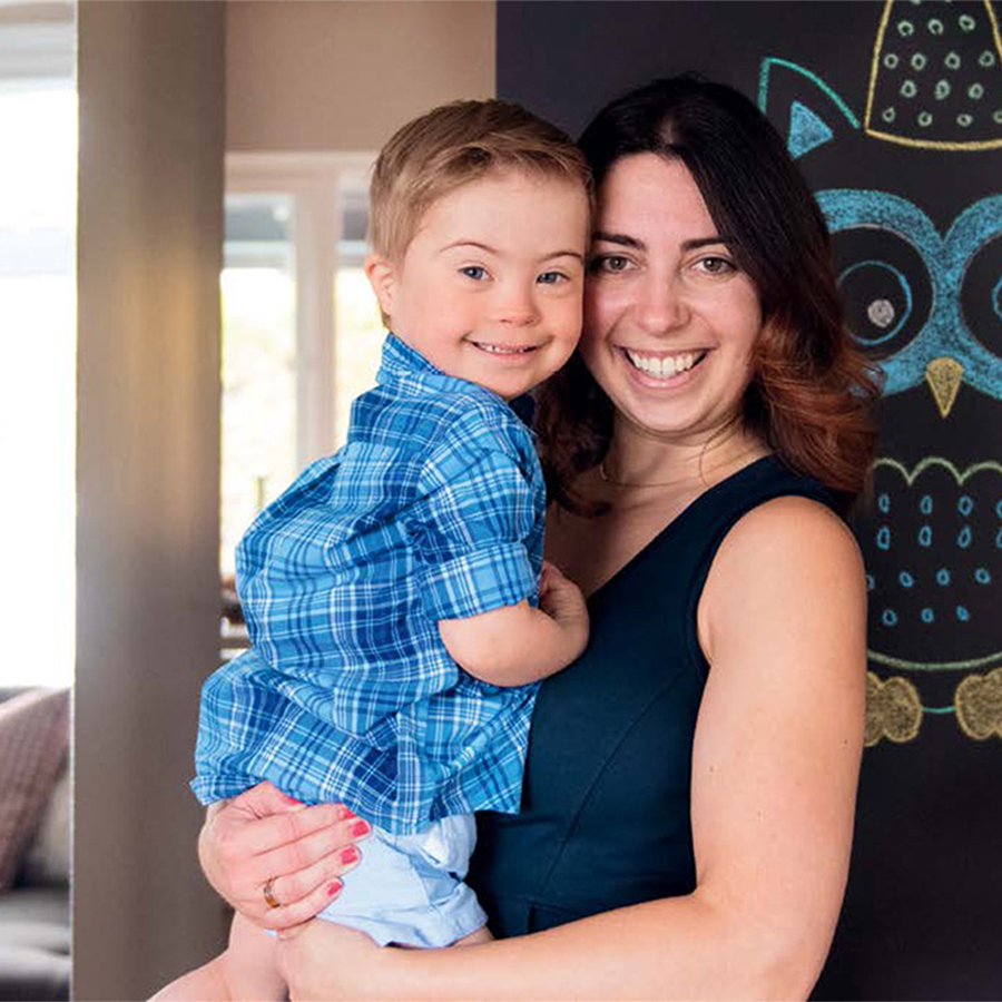 Mother holds young boy in her arms as they both smile