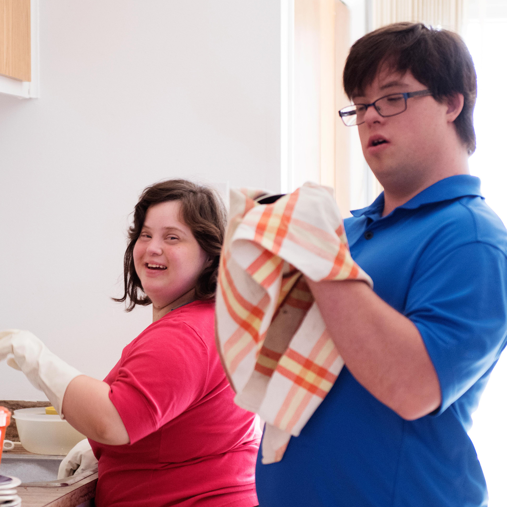 A man and a woman are doing the dishes together in a kitchen