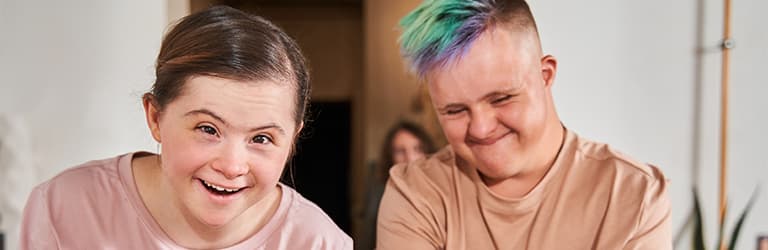 Girl laughing at camera next to a boy smiling happily