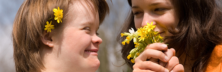 Mother smelling a bunch of yellow flowers held by her daughter