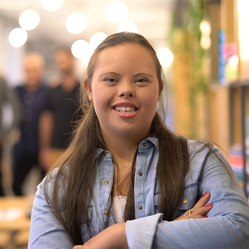 Young woman smiling with her arms crossed in a library