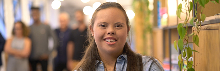 Young woman smiling with her arms crossed in a library