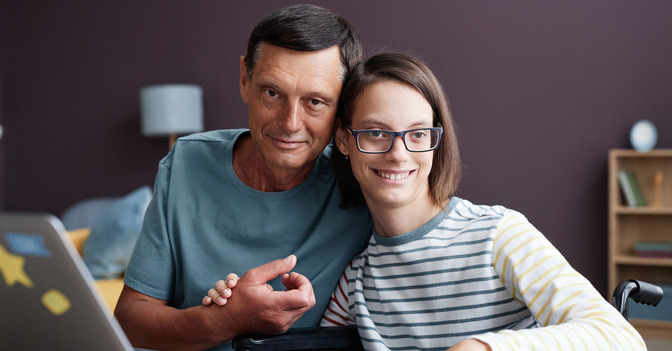 Daughter and father sitting at desk with computer